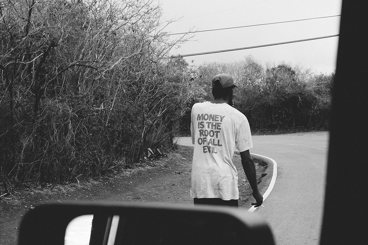 a man walking while wearing a t-shirt that reads, "money is the root of all evil."